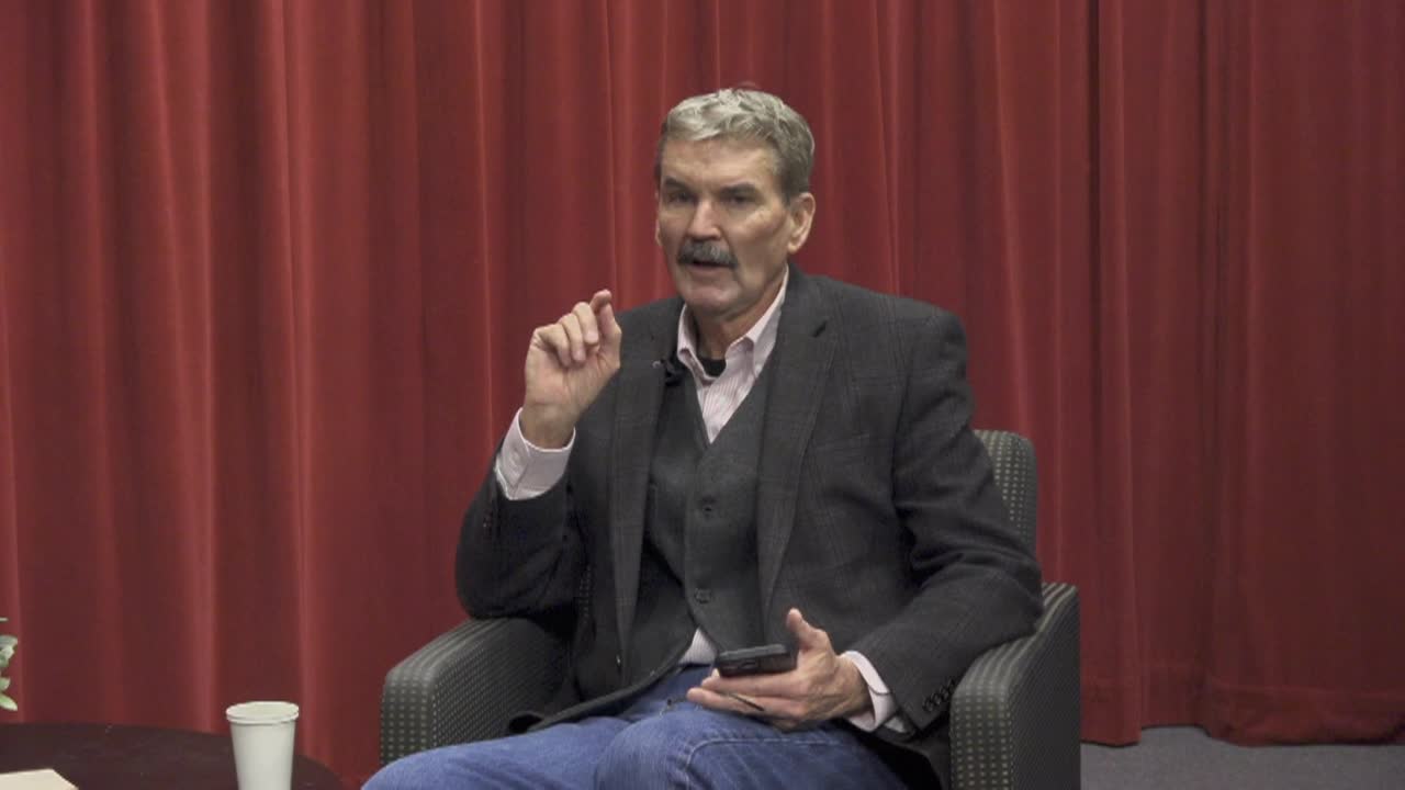 Red curtain background. Older man in a vest and blazer