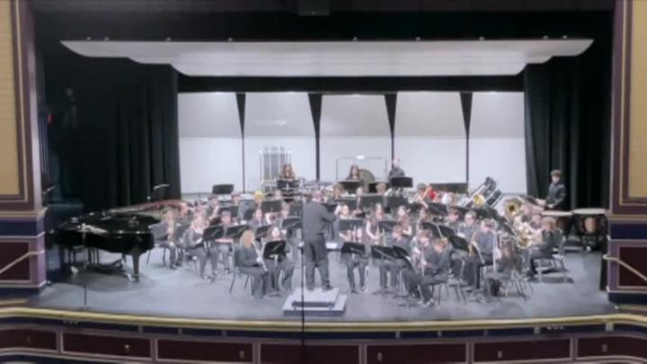 Students on a stage with various band instruments