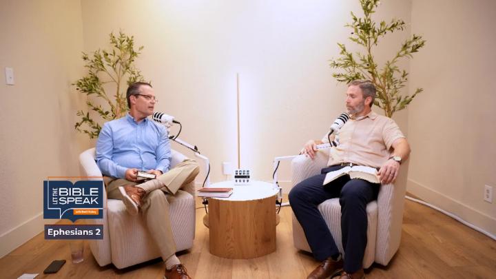 Light colored walls with plants in the background. Man in a blue button up seated to the left behind a podcast mic. Man in a cream button up seated to the right behind a podcast mic. Let the Bible Speak logo in lower left corner