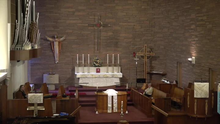 brick walls. Altar with candles in center. Statue of Jesus to the left. Pulpit in front of alter.