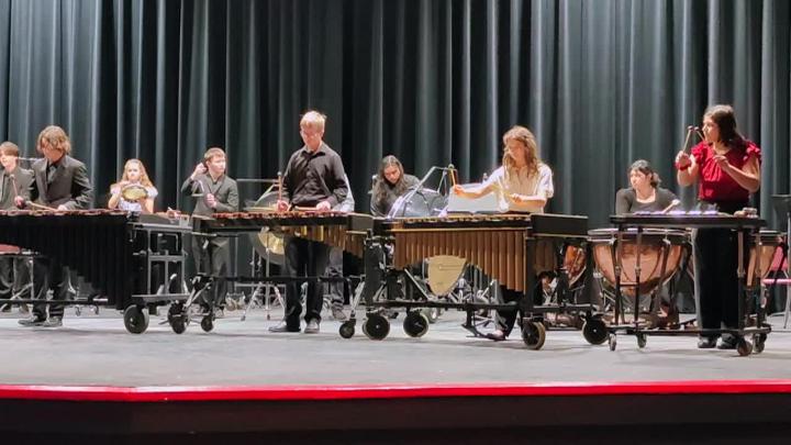 Students on stage playing various percussion instruments