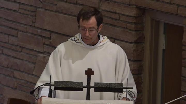 Priest in white robe. Brick background