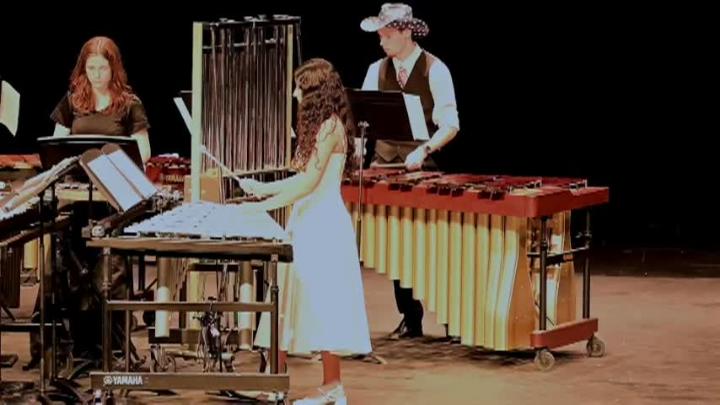 Students on stage in front of various instruments playing them