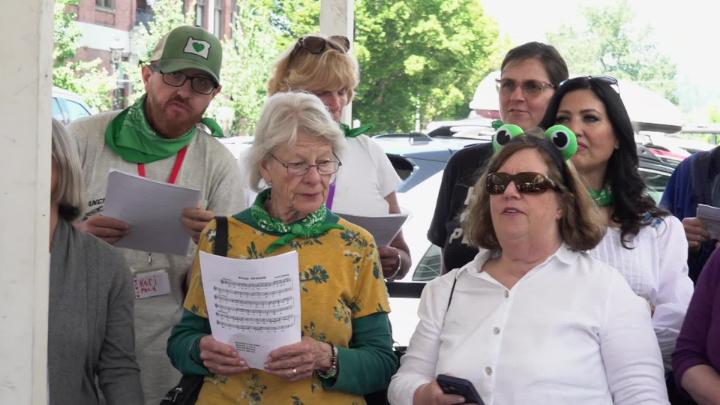 A chorus of people dressed in white outside.