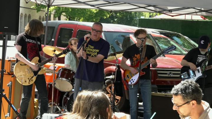 Musicians outside with a red car in the background