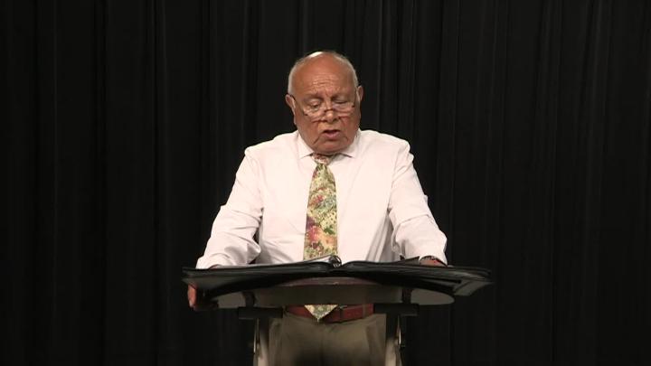 Older man in a button up and tie standing in front of a podium