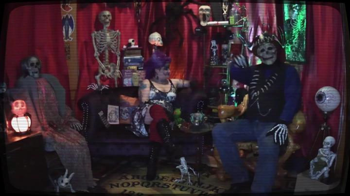 Horror items in the background with people dressed in ghoulish gear