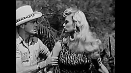 Black and white movie clip. Man in a safari hat to the left and a woman with light hair looking at man in the middle