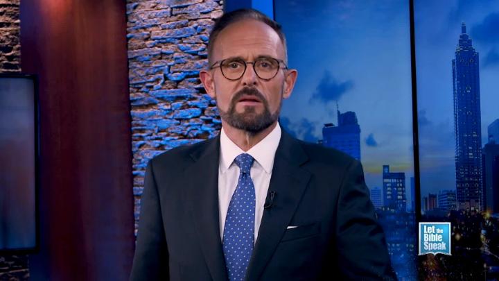 Man in a dark suit and glasses in the center. Blue cityscape in the background. Let the Bible Speak logo in bottom right corner