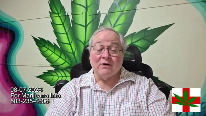 Older man in glasses and a button up shirt seated in front of a brick wall with a large green cannabis leaf behind him.