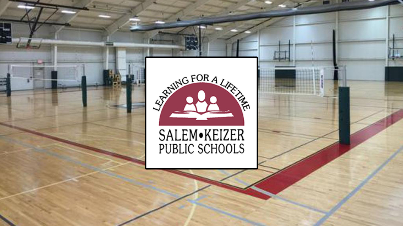 Basketball court with volleyball nets on it. Maroon and white Salem-Keizer Public Schools logo in the center