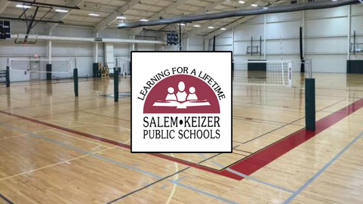 Basketball court with volleyball nets on it. Maroon and white Salem-Keizer Public Schools logo in the center