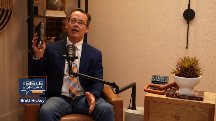Man in a blue suit sitting in front of a podcast mic. Yellow toned walls in the background with a small bookshelf. Blue Let The Bible Speak logo in the bottom left corner.