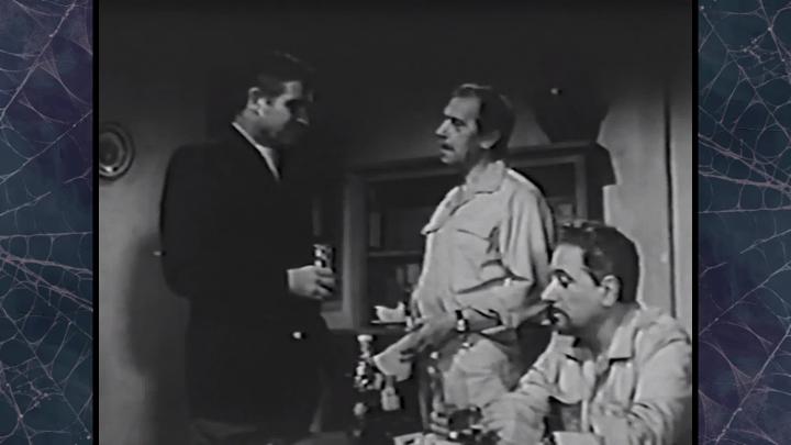 Black and white movie image of three men in a room.