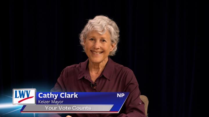 Black background. Woman in a plum colored button up in the middle. Lower thirds to the bottom left with red, white and blue LWV logo. White words on a blue background: Cathy Clark Keizer Mayor Your Vote Counts NP
