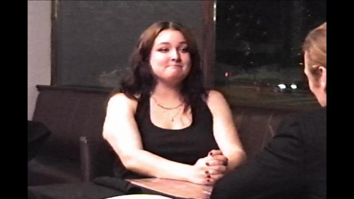 Woman dressed in black seated at a table.