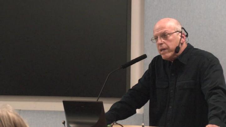Man in black talking into a podium mic