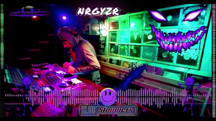 Glow in the dark dj room with a dj at a turntable. White word at top middle: Nrgyze