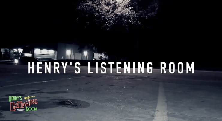 Black and white parking lot with white words in the center: "Henry's Listening Room" and a red, green and yellow Henry Turner logo in the lower left.