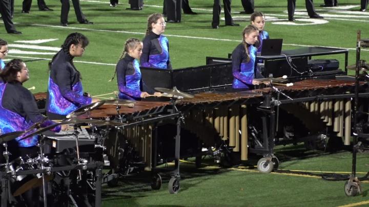 football field with marching band instruments and people dressed in black and purple