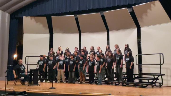 Stage with several students in black standing on it.