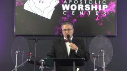 Preacher on stage with Apostolic Worship Center logo in background