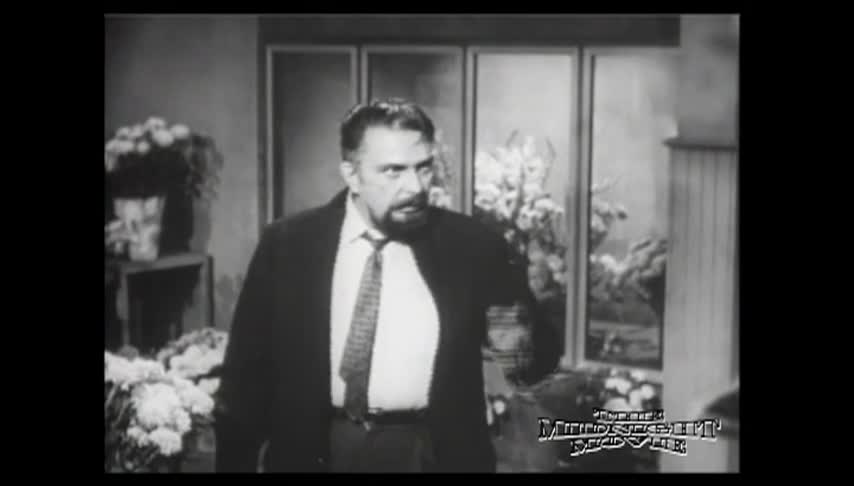 Black and white movie clip with a man in a suit in the middle.