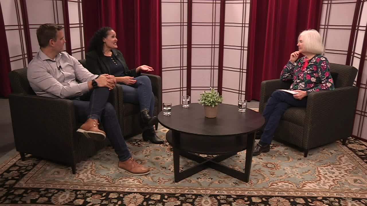 Man and woman seated to the left. Coffee table in the center. Older woman seated to the right.