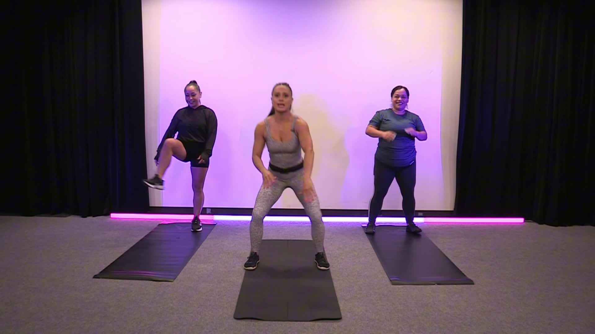 Purple lighted background with three people doing exercises
