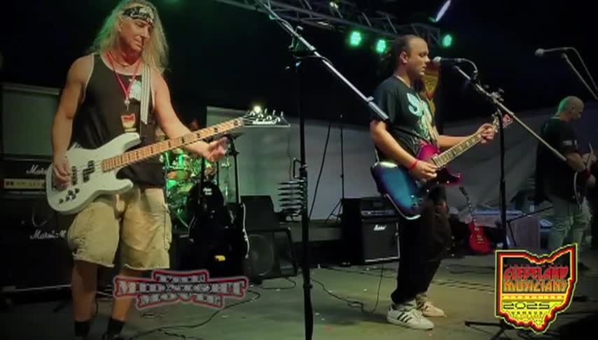 Two men with guitars standing in front of mics